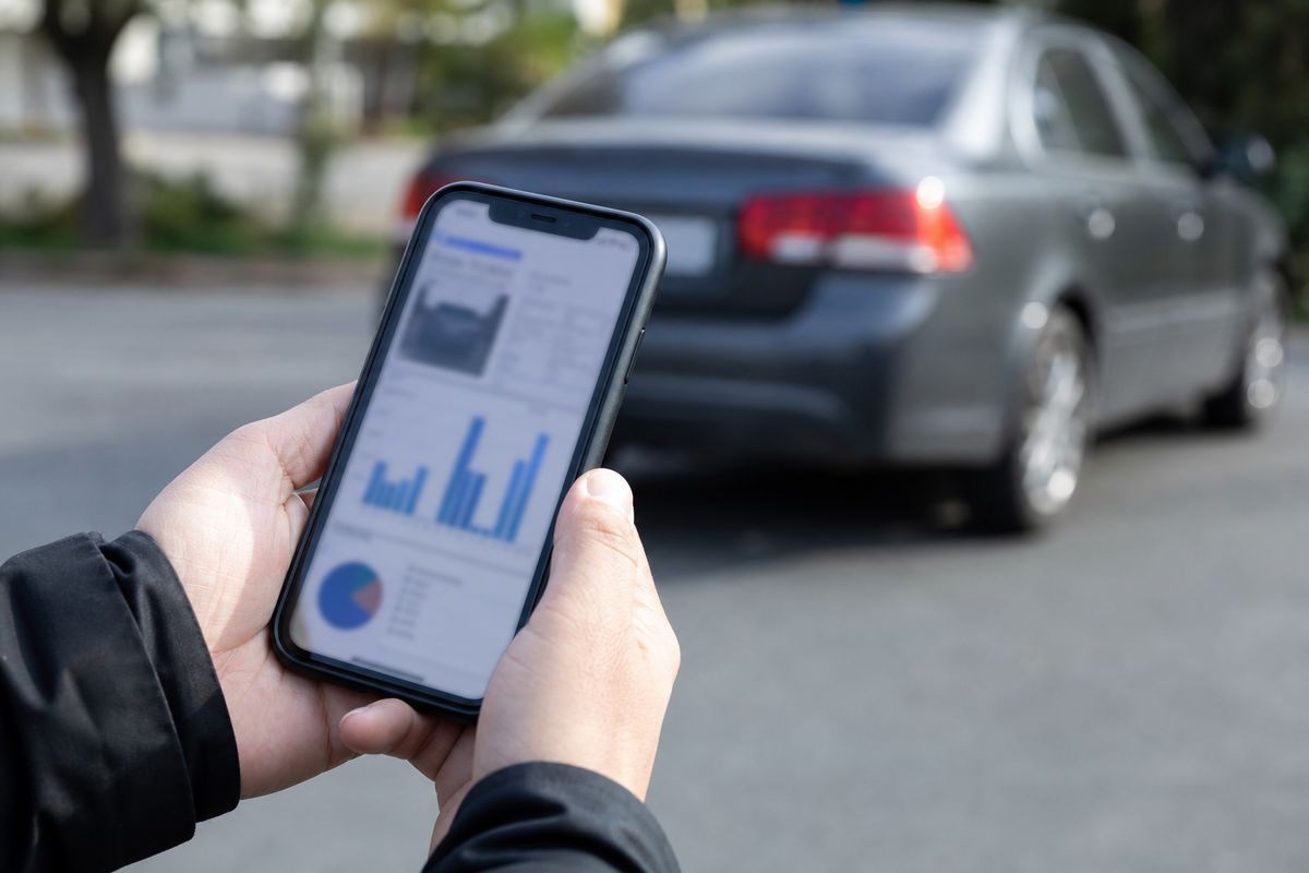 Покупатель изучает отчёт по VIN автомобиля на экране телефона